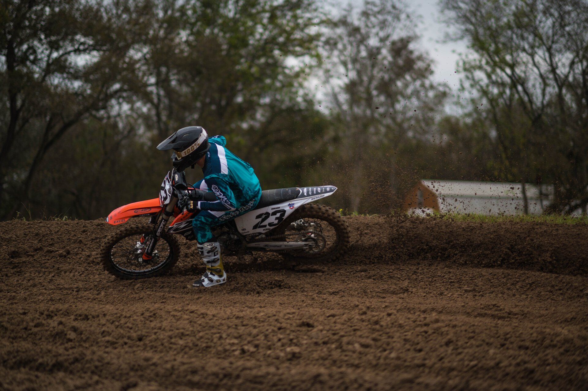 A rider carving a dirt berm on an orange motocross bike at Creekside MX